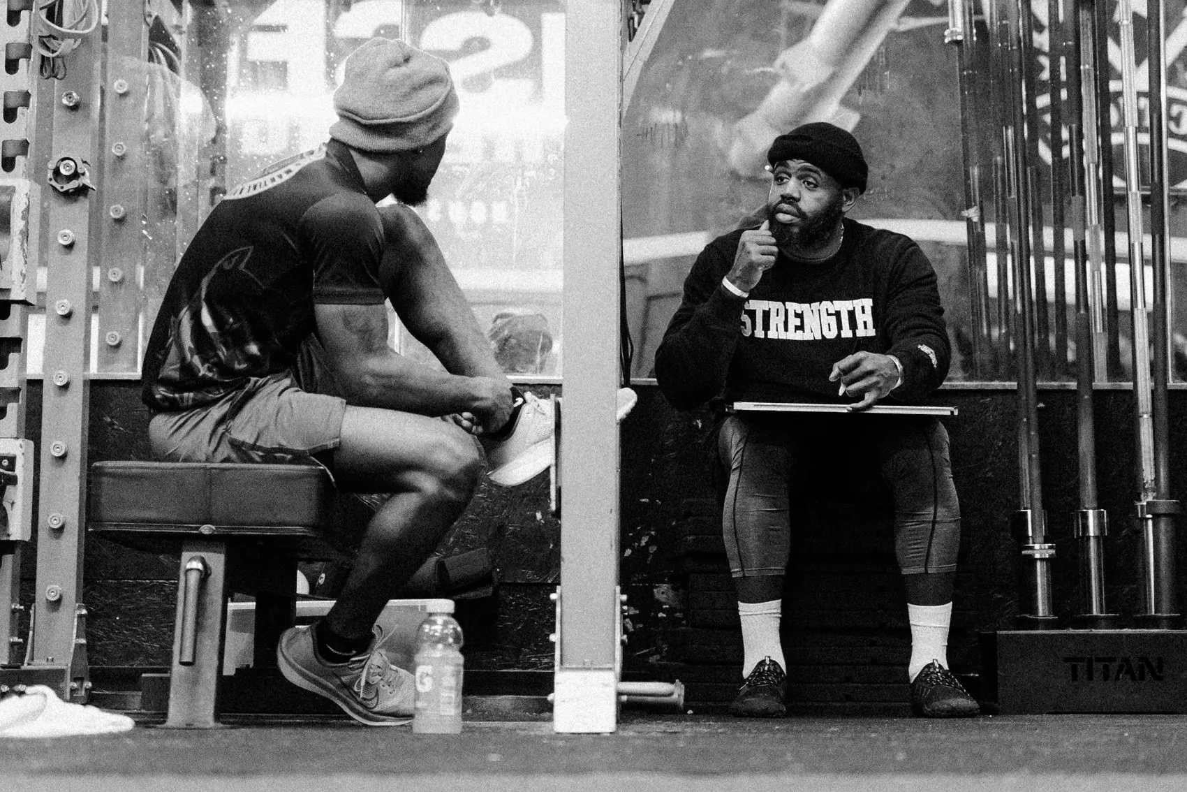 Coach reviewing an athlete's numbers between sets on the gym floor