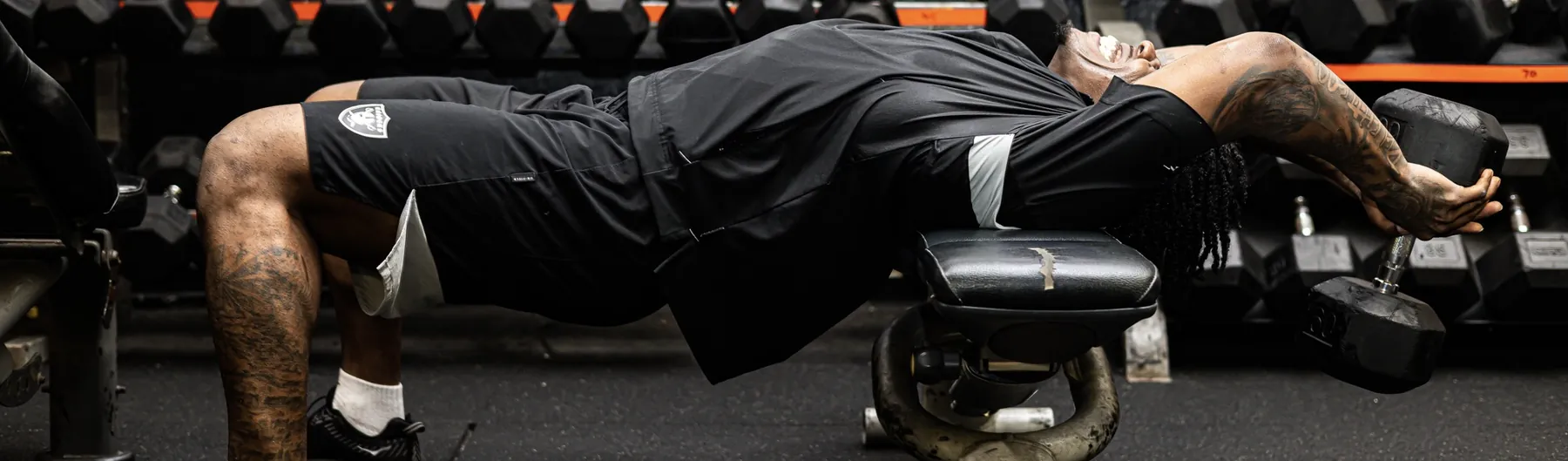 BOSX client holding a loaded dumbbell bridge on the gym floor